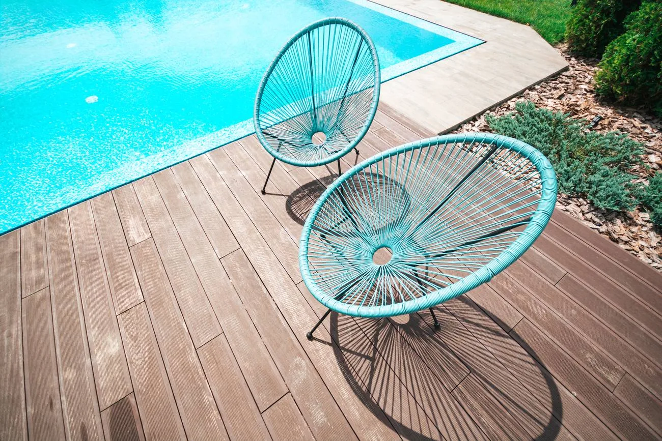 Zwei Stühle auf einem Holzdeck neben klarem Wasser